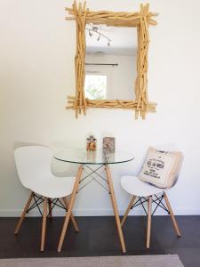 uma mesa de vidro e duas cadeiras brancas e um espelho em Chambre d'hôtes LE SECADOU em La Ciotat