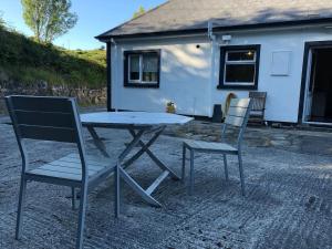 a picnic table and two chairs in front of a house at Modern Six Bedroom House Westport in Westport