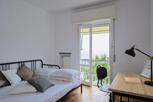 Un dormitorio con una cama y un escritorio y un balcón. en Casa Bianca a Bogliasco by Wonderful Italy, en Bogliasco