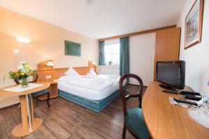 a hotel room with a bed and a desk with a television at Hotel Ostseewoge in Graal-Müritz