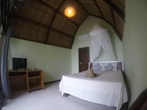 a bedroom with a white bed and a television at Krisna Bungalows and Restaurant in Sekotong
