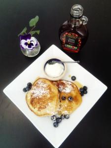 a plate of pancakes with blueberries and a bottle of syrup at No 12 B&B in Dungarvan