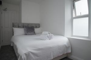 1 dormitorio con 1 cama blanca y 2 toallas en TLK Apartments & Hotel - Beckenham, en Beckenham