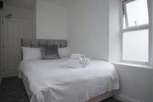 a bedroom with a white bed with two towels on it at TLK Apartments & Hotel - Beckenham in Beckenham