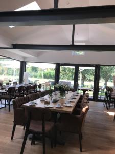 un comedor con mesas, sillas y ventanas en Landcafe Neumann en Bad Zwischenahn