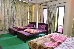 a bedroom with two beds and a couch and a window at Lahore Hotel in Swat