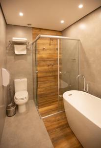 a bathroom with a tub and a toilet and a shower at Pousada Armazém 26 in Tiradentes