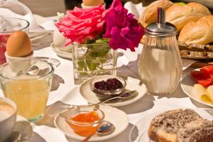 une table avec un vase de fleurs et des assiettes de nourriture dans l'établissement Pension Sonnheim, à Gargazzone