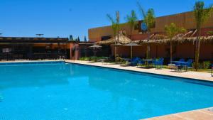 ein großer blauer Pool mit Stühlen und Sonnenschirmen in der Unterkunft L'AUBERGE DE TENNIS MSC in Marrakesch