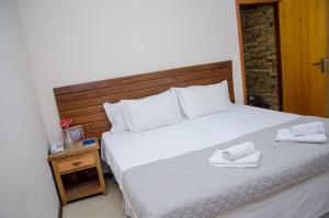 a bedroom with a large bed with two white towels on it at Hotel Pousada La Belle in Itaguaí