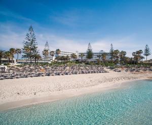 a beach with lounge chairs and the ocean at Nissi Beach Resort in Ayia Napa