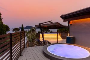 a hot tub on a deck with an umbrella at Lamasu RioVerde - Lago di Garda in San Felice del Benaco