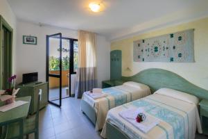 a hotel room with two beds and a table at Hotel Cala Dei Pini in Porto Pino