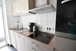 a kitchen with white cabinets and a black stove top oven at Ferienwohnung Troisdorf in Troisdorf +16 photos