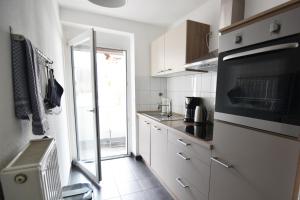 a kitchen with white cabinets and a black appliance at Ferienwohnung Troisdorf in Troisdorf