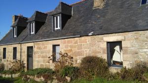 an old stone house with a black roof at Gite de Kerianégan in Pleumeur-Bodou