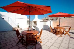2 Tische und Stühle mit roten Sonnenschirmen auf einer Terrasse in der Unterkunft Appartamenti Fusaro in Specchia