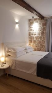 a bedroom with a white bed with a brick wall at Apartments Milion in Korčula