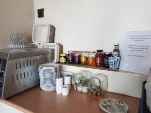 a kitchen counter with plates and cups and a microwave at Victoria Lodge in Shanklin