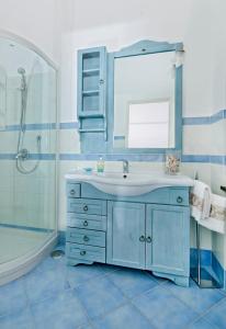 Baño azul con lavabo y espejo en Parco Vittoria Holidays House, en Anacapri