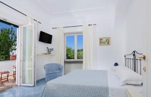 a white bedroom with a bed and a balcony at Parco Vittoria Holidays House in Anacapri