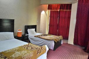 a hotel room with two beds and red curtains at Zara Residence 1 in Swat