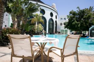 a table and chairs next to a swimming pool at Hotel LIVVO Volcán Lanzarote in Playa Blanca