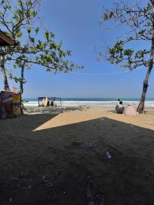 a person sitting on the beach with their feet in the sand at Villa Family Pantai Citepus Pelabuhanratu in Citepus
