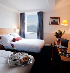 ナポリにあるSan Giacomo 32 Residenceのベッド2台と食料品のトレイが備わるホテルルームです。