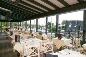 a restaurant with white tables and chairs and windows at Hotel LIVVO Volcán Lanzarote in Playa Blanca