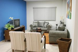 a living room with a couch and chairs and a tv at Monte Castro Executive Hotel in Araguari