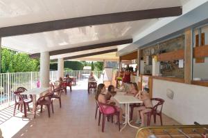 a group of people sitting at tables in a restaurant at Camping La Combe in Barjac