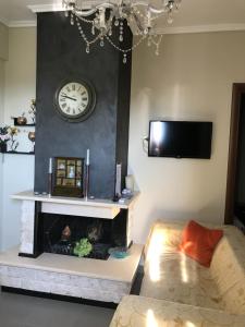 a living room with a fireplace and a clock on the wall at Vasilia in Nea Irakleia