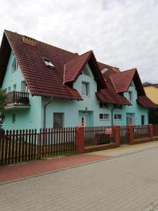 a blue house with red roof at Pokoje Gościnne U Dany in Jarosławiec