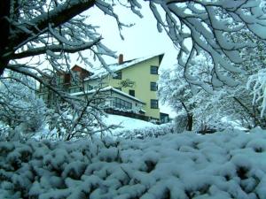 a snow covered yard with a house in the background at Landhotel BurgenBlick Garni & Tagungshotel in Erfurt