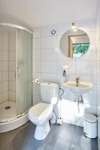 a white bathroom with a toilet and a sink at Metropolis Domki in Sopot