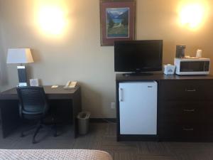 a hotel room with a desk with a tv and a refrigerator at Days Inn by Wyndham Hinton in Hinton