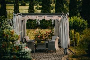 - un kiosque avec des chaises et une table dans le jardin dans l'établissement Pensjonat Jurkowski Wellness & Spa, à Ochotnica Dolna