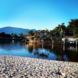 a beach next to a body of water with palm trees at Suítes Km18praia in Barra do Una +10 photos