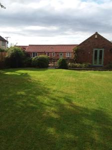 a large yard with a brick building and a grass field at Swallow cottage in Louth