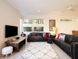 a living room with a black couch and a flat screen tv at Coolum Street 41 Dicky Beach in Caloundra