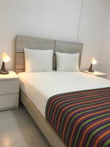 een slaapkamer met een groot wit bed met 2 lampen bij Charming episode in Lissabon