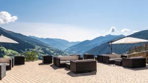 Eine Terrasse mit Stühlen und Sonnenschirmen mit Blick auf einen Berg in der Unterkunft Panorama Resort Taljörgele in Ridnaun