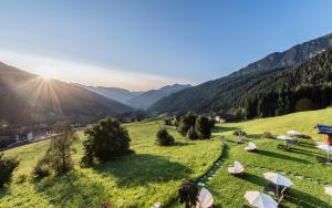 Blick auf ein Feld mit Sonnenschirmen und Bergen in der Unterkunft Panorama Resort Taljörgele in Ridnaun