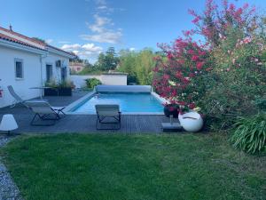 a swimming pool in a yard with chairs and flowers at Le Clos du Pontet in Orliénas