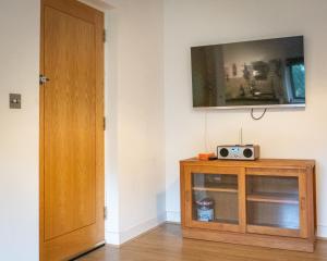 a room with a wooden cabinet with a tv on the wall at 2 Ringles Place in Uckfield