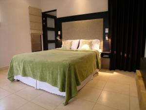 sypialnia z łóżkiem z zielonym kocem i poduszkami w obiekcie Condominos Las Ventanas w mieście Paraíso