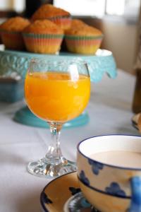 a glass of orange juice on a table with cupcakes at Casa Rural Francisco Pizarro in Herrera del Duque