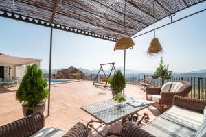 un patio con mesa, sillas y un columpio en Villa with views and private pool near Malaga., en Colmenar