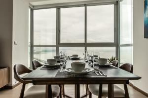 stół jadalny z krzesłami i duże okno w obiekcie Home Suite Ocean View Apartment - PH Quartier Del Mar w Panamie